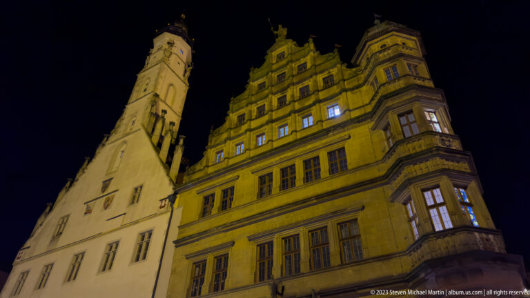 Floodlit Rothenburg Town Hall complex with ornate Renaissance façade, stepped gables, projecting bays, and adjoining tower.