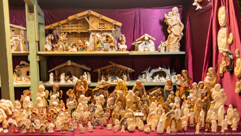 Large display of nativity figures, Holy Family groups, animals, angels, and small stable crèches on several levels.