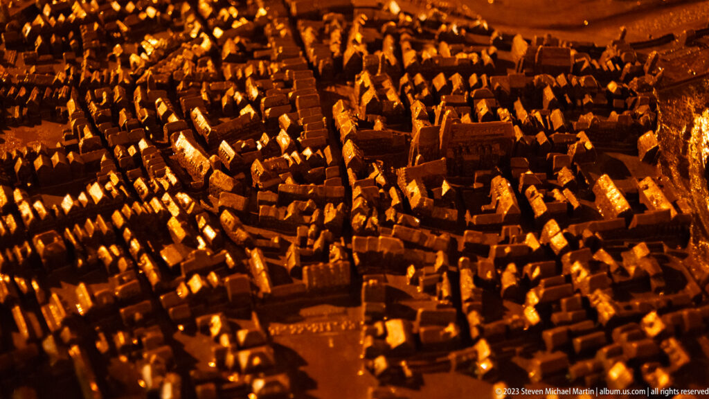 Warmly illuminated scale model showing dense roofs, streets, towers, and buildings of Rothenburg’s historic center.