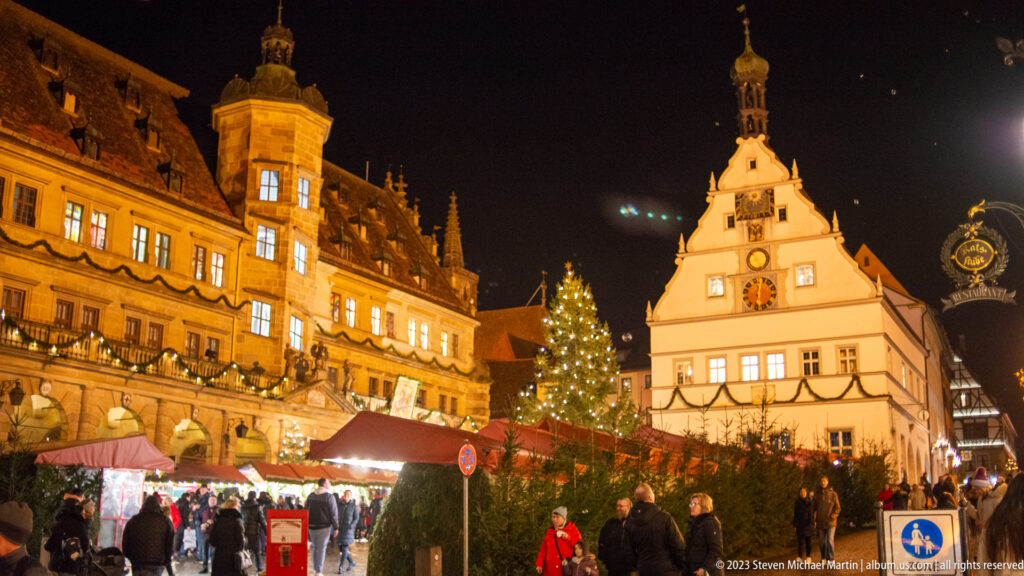 Christmas market in Rothenburg’s Marktplatz between the illuminated Rathaus and white stepped-gable Ratstrinkstube.