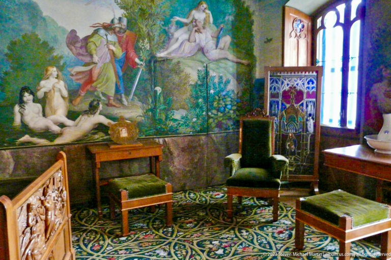 Green upholstered chair and Gothic-style window in a Hohenschwangau room covered with mythological landscape murals.