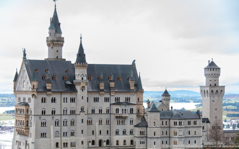 Close telephoto view of Neuschwanstein Castle showing its palace block, steep roofs, arched windows, and towers.