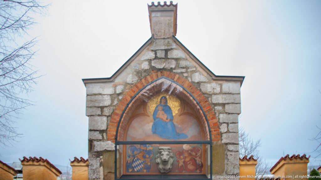 Pointed painted panel of the Virgin and Child above heraldic motifs in a small stone gable at Hohenschwangau Castle.