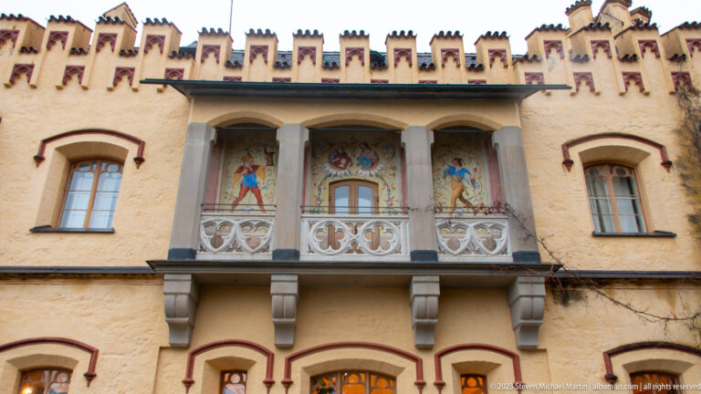 Painted balcony with tracery panels and figurative decoration on the ochre facade of Hohenschwangau Castle.