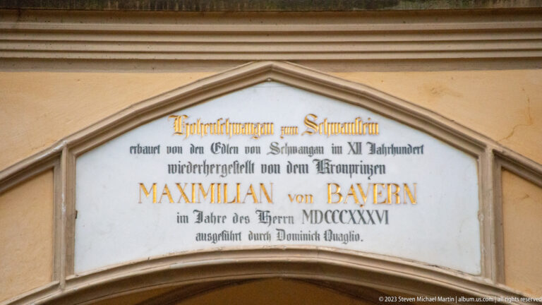 German inscription in a pointed panel naming Maximilian of Bavaria in large gold lettering.