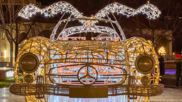 Front close-up of a wireframe Mercedes-Benz roadster light sculpture with circular headlights and a large three-pointed-star grille emblem.