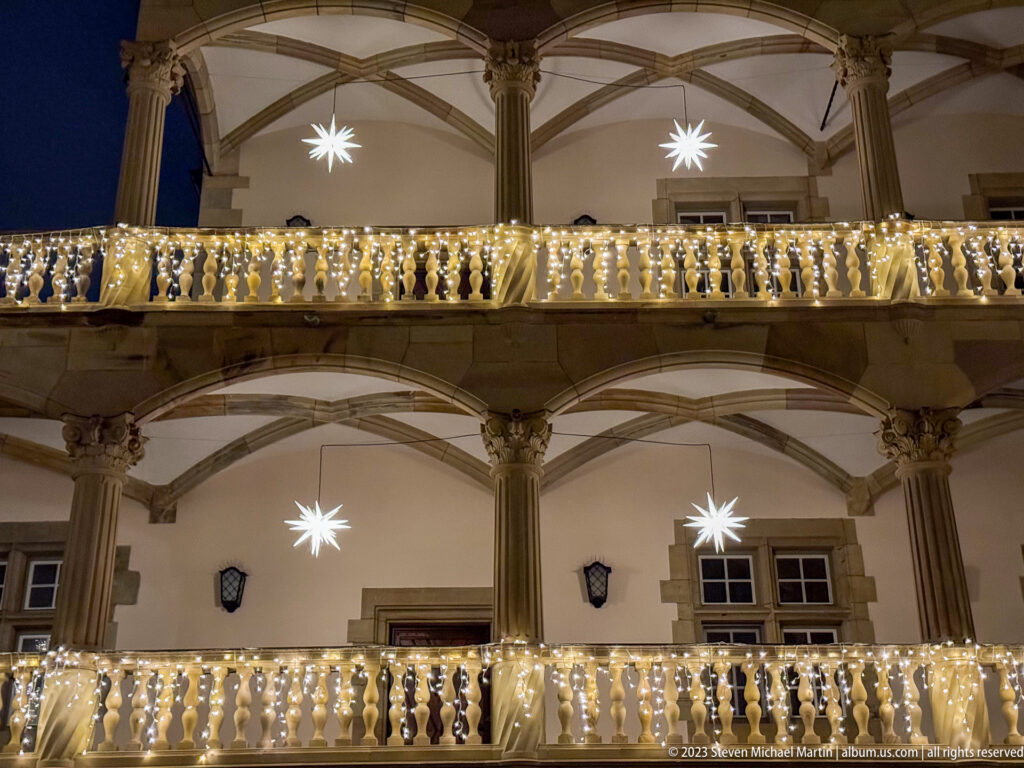 Renaissance arcades and balustrades of Stuttgart’s Altes Schloss courtyard decorated with warm string lights and hanging star lanterns.