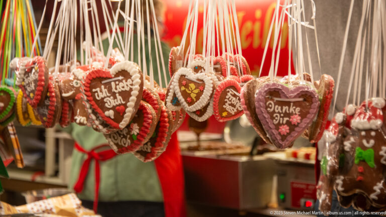 Heart-shaped gingerbread cookies hanging by ribbons, decorated with icing and German messages including Ich liebe Dich and Danke Dir.