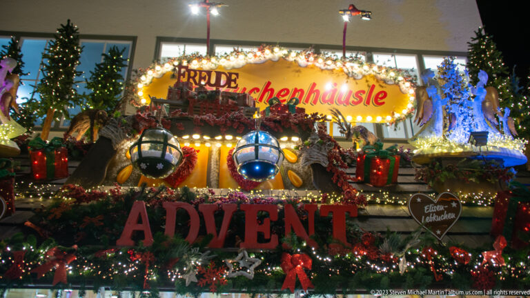 Christmas market stall roof packed with garlands, gifts, ornaments, winter figures, and large red letters spelling ADVENT.
