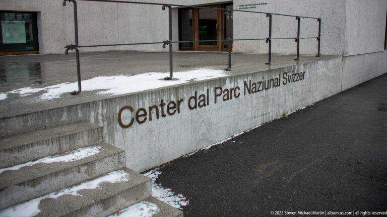 Concrete entrance steps and ramp beside large lettering reading 'Center dal Parc Naziunal Svizzer.'
