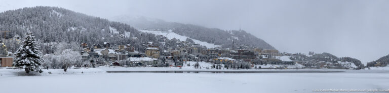 St. Moritz buildings line the far shore of the frozen lake beneath a snowy mountain and visible ski run.
