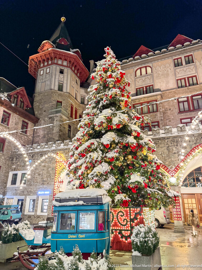 Blue Palace Hotel display vehicle beneath a towering decorated Christmas tree, with the historic hotel façade rising behind.