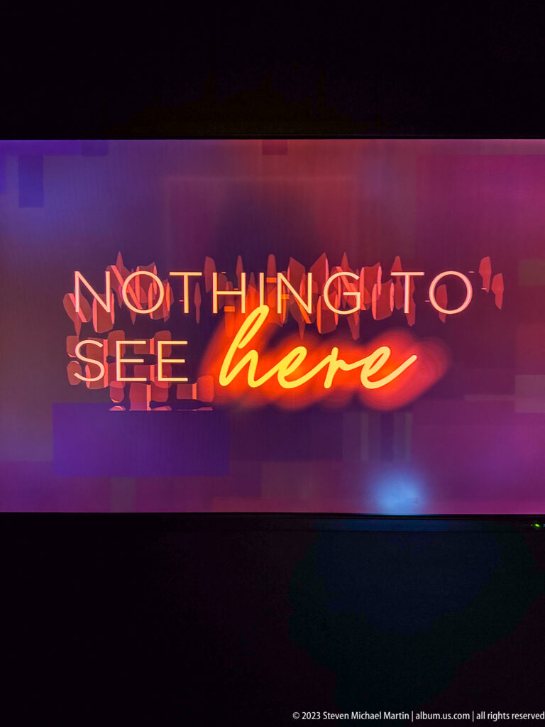 Neon wall sign reading 'NOTHING TO SEE here,' with block letters and a glowing cursive final word.