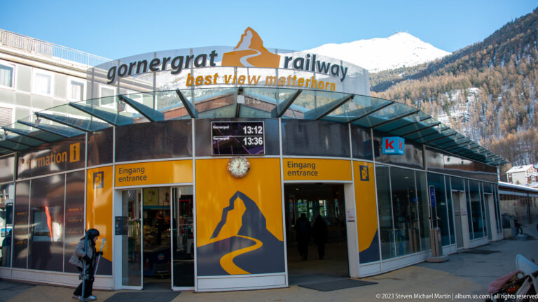 Gornergrat Railway station entrance with yellow panels, glass canopy, departure display, and best view matterhorn slogan.