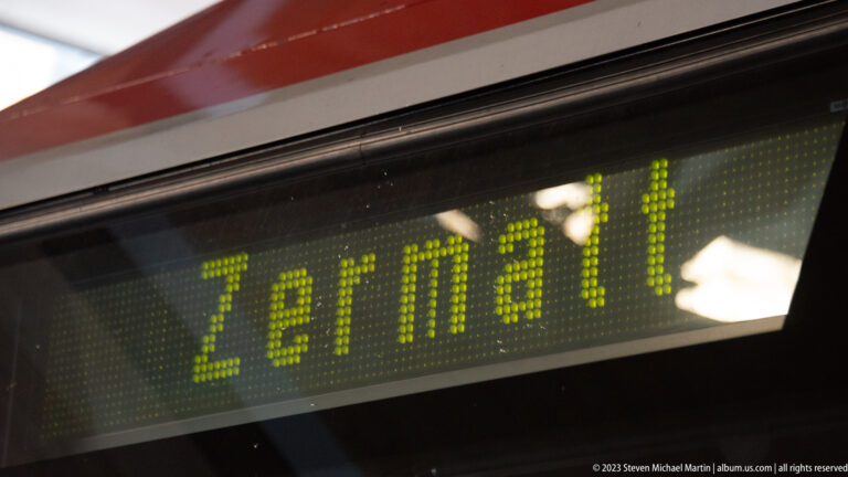 Close-up of a green electronic rail display spelling “Zermatt” in illuminated dot-matrix letters.