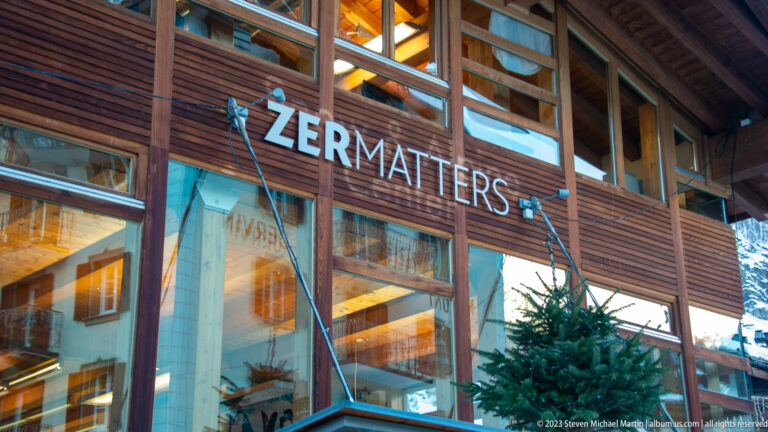 Timber-and-glass storefront with large ZERMATTERS lettering and warm light glowing from inside.