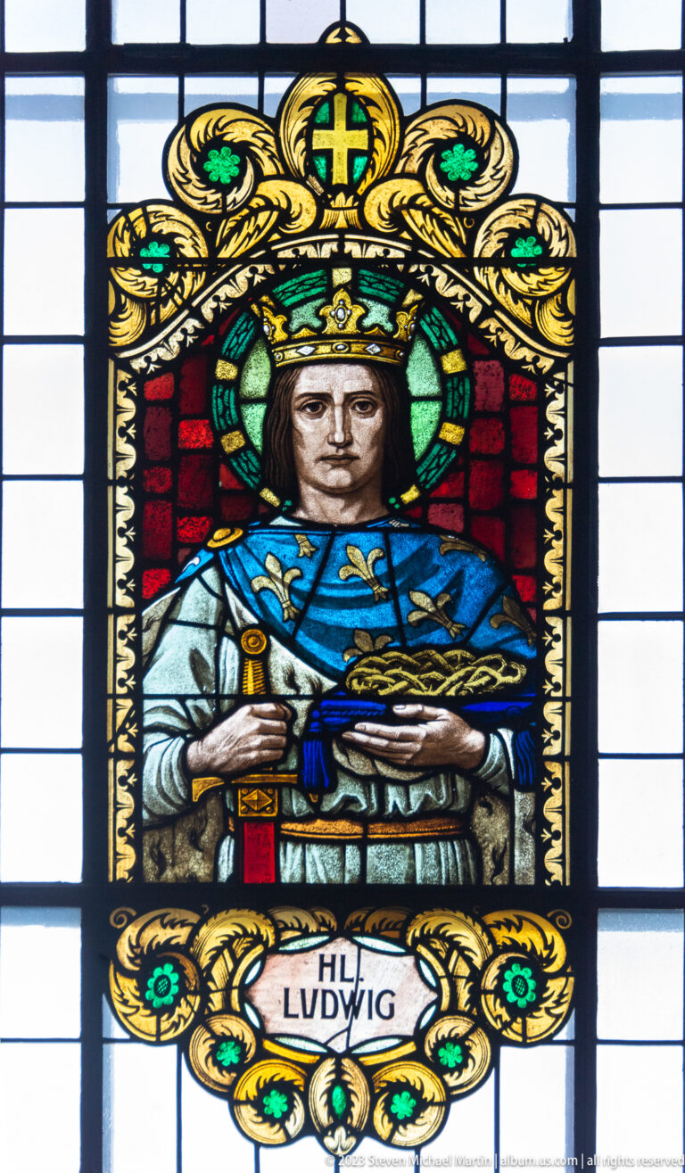 Stained-glass Saint Louis wearing a crown and blue robe, holding a sword above the inscription HL. LUDWIG.