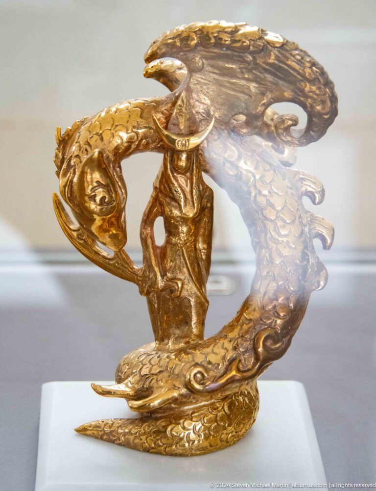 Gold figure with curved decorative elements.
