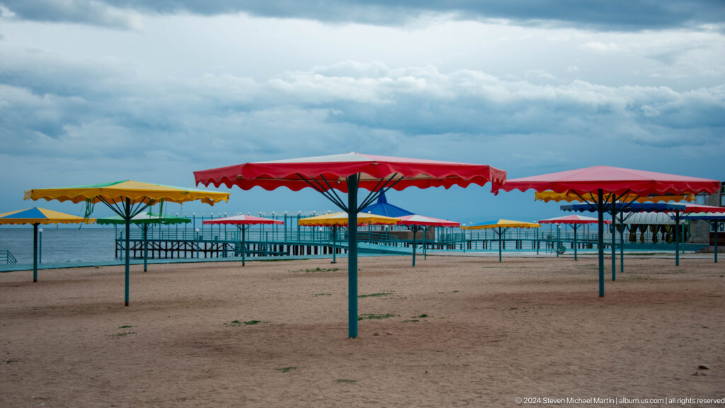 Empty lakeside beach with colorful shade canopies.