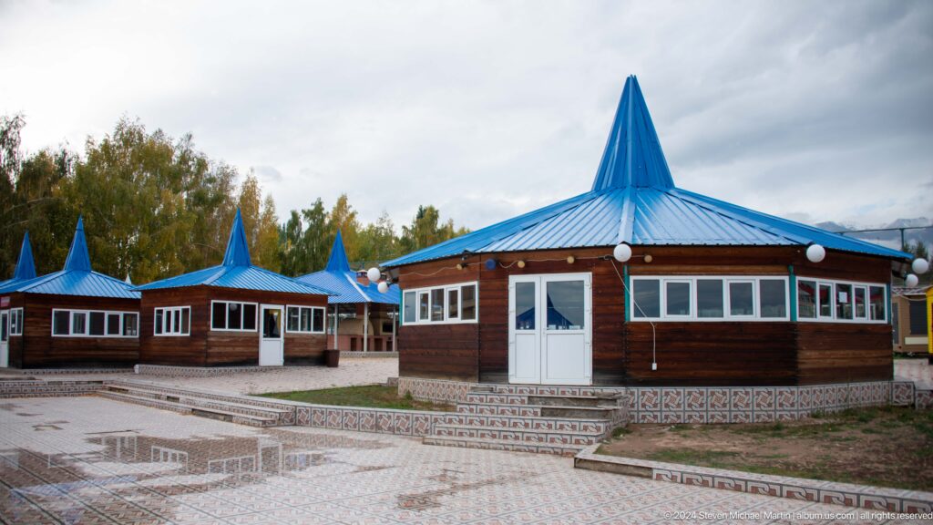 Low lakeside buildings with bright blue roofs.