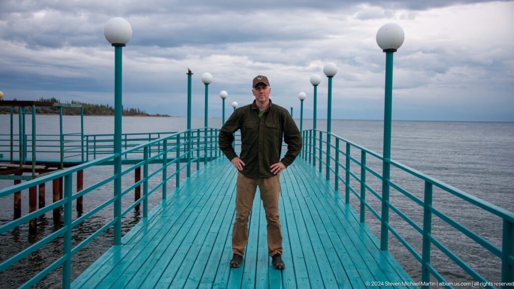 Man standing on a turquoise pier.