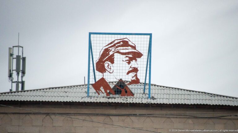 Rooftop sign with a red profile portrait.