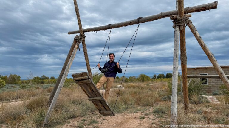 Person on a second rustic swing by the lake.