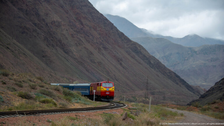 Locomotive rounding a bend in a mountain valley.