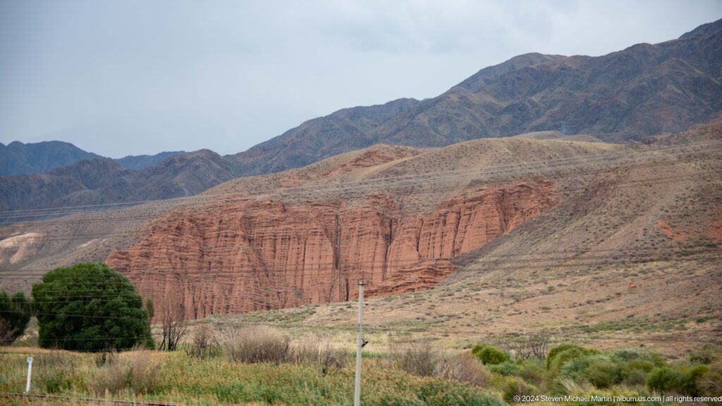 Red sedimentary cliffs beneath dark mountains.