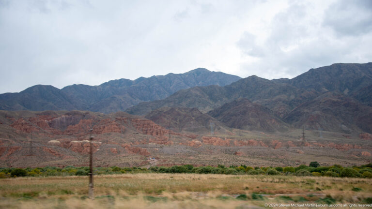 Wide red foothills before a dark mountain range.