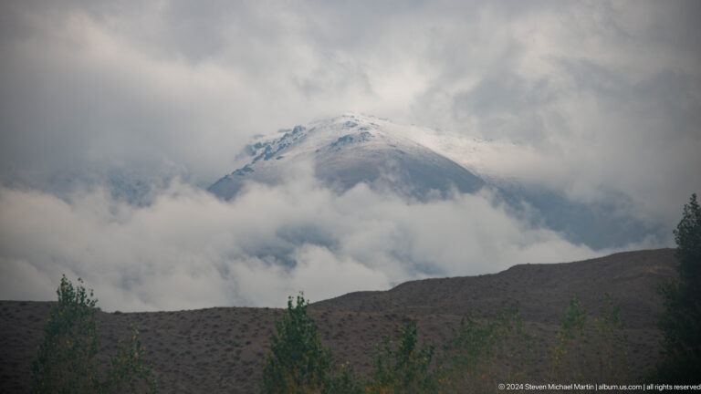 Snowy mountain summit emerging through clouds.