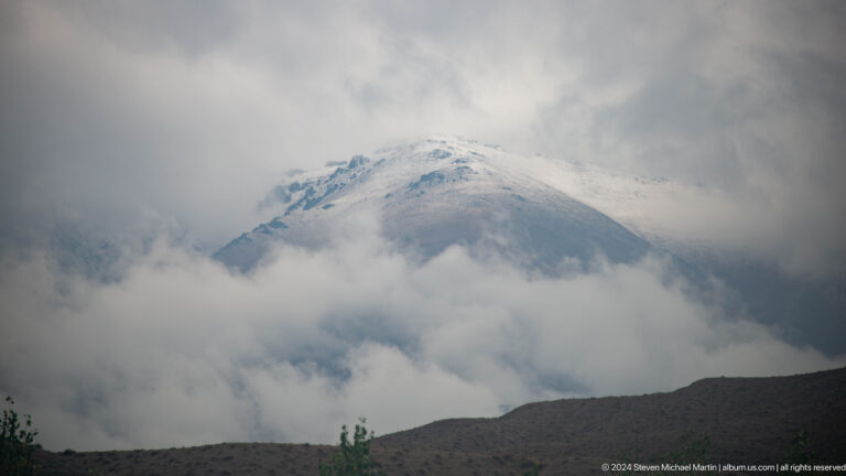 Snow-covered peak partly hidden by dense clouds.