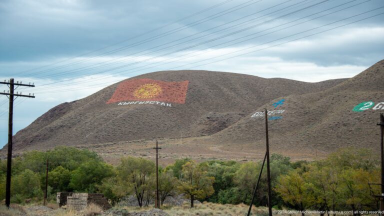 Distant hillside flag above trees and utility poles.