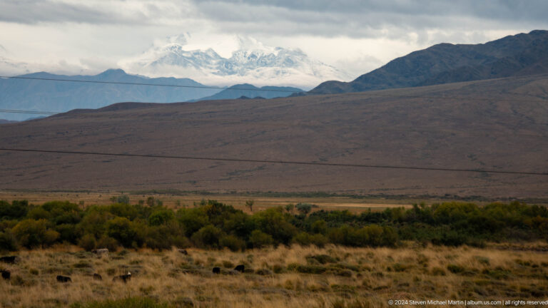 Broad brown plateau below distant snowy peaks.