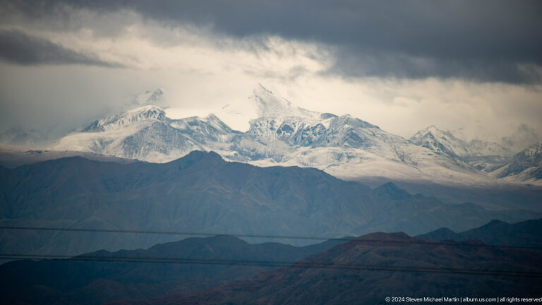 Snowy mountain chain beneath dark clouds.