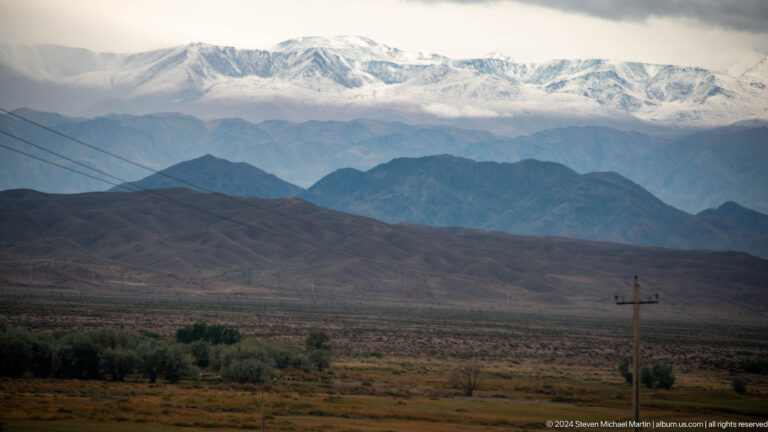 Layered ridges and snow mountains beyond the plain.