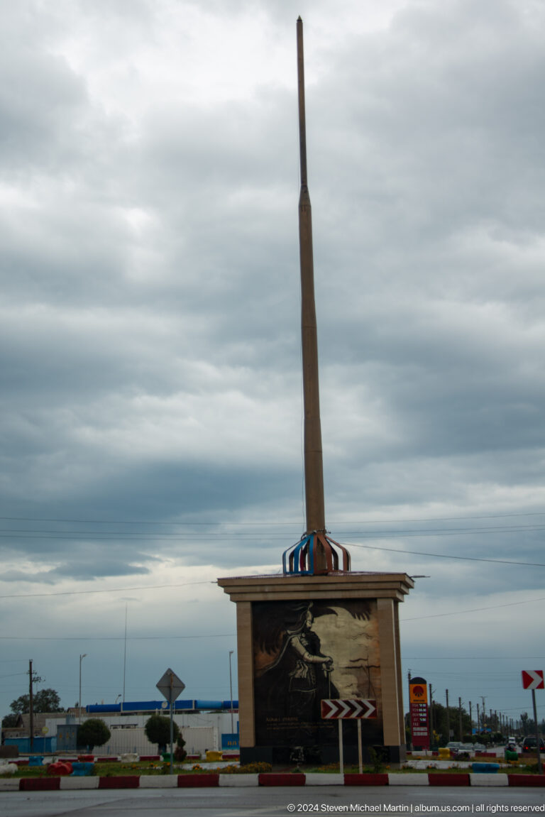 Tall flagpole base beneath a cloudy sky.