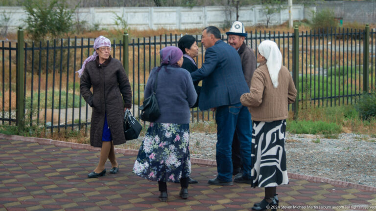 Older residents gathered outdoors near a fence.