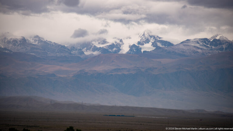 Snow mountains beneath dramatic layered clouds.