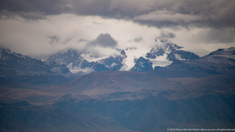 Wide view of cloud-wrapped snowy peaks.