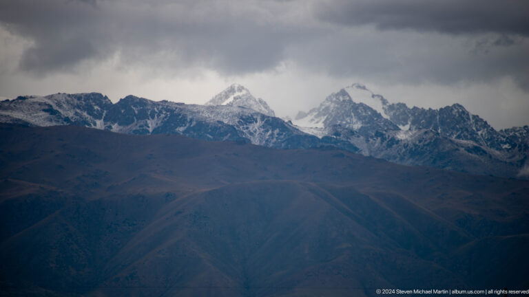 Dark ridges before a jagged snowy range.