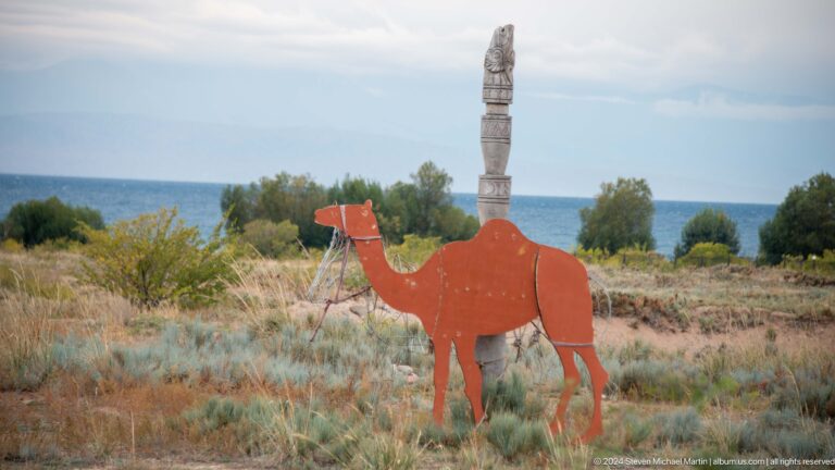 Red camel silhouette with carved vertical figure.