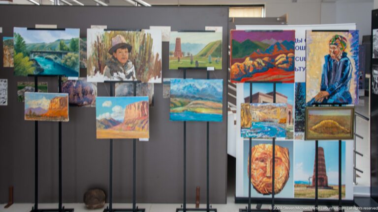 Outdoor display of colorful landscape paintings.
