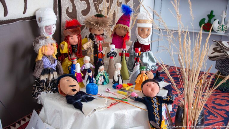 Table crowded with handmade dolls and crafts.