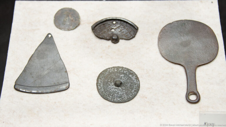 Metal tools and flat implements on a display surface.