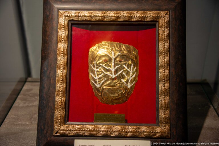 Framed gold ornament against red backing.