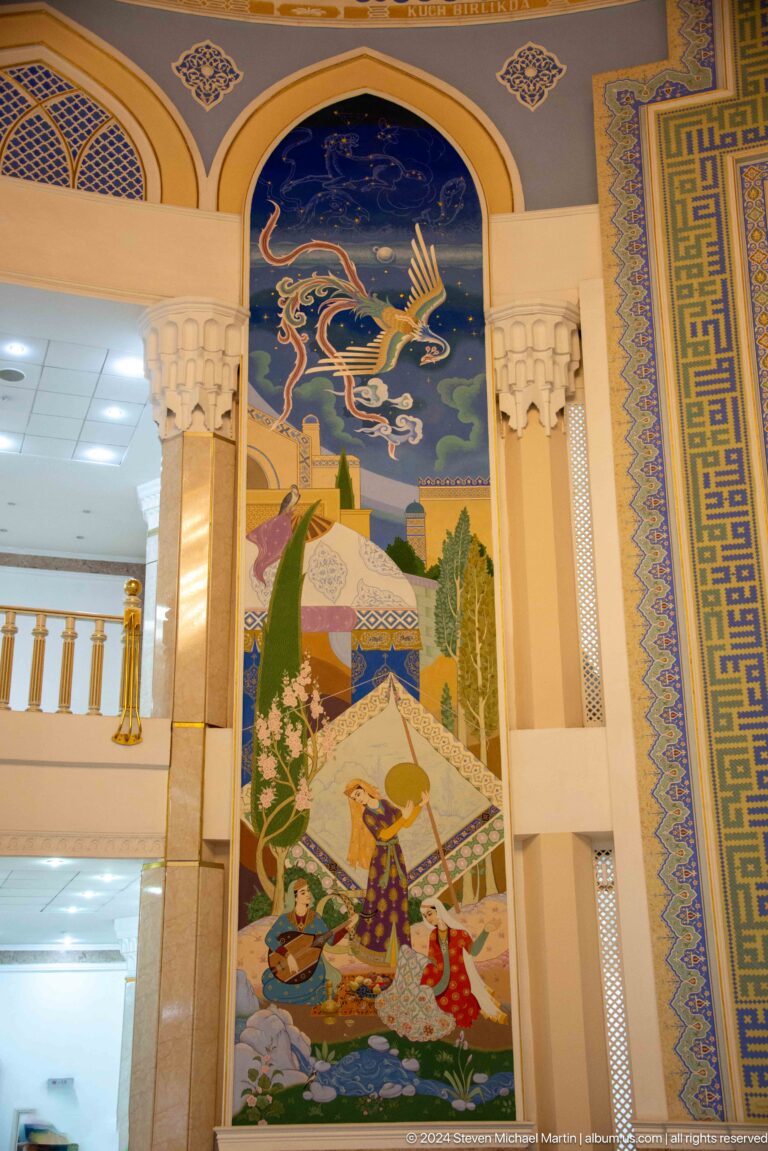 Vertical mural panel with domed and tent-like buildings, tall trees, a small figure, and a fantastic motif above.