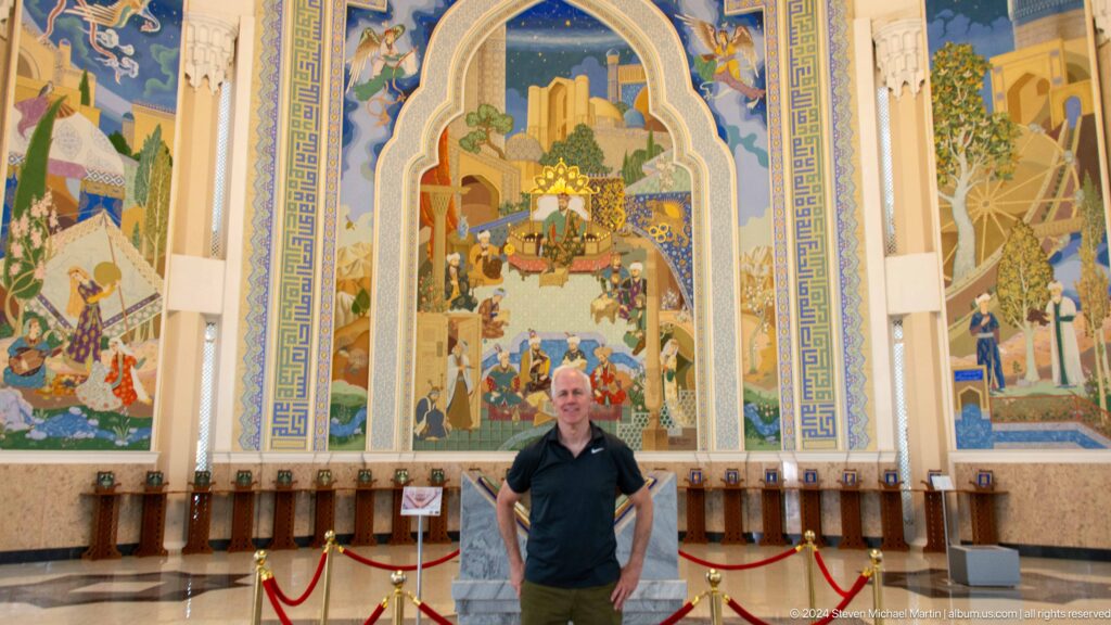 Man standing with hands at hips before the large mural.