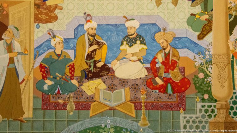 Four seated men around an open book on a wooden stand.
