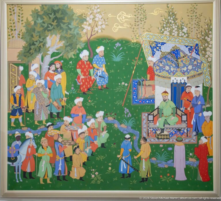 Crowd gathered before a ruler under a decorated canopy.